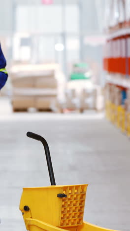 Male-warehouse-worker-moping-floor