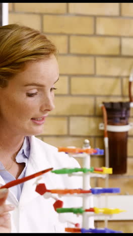 Teacher-assisting-school-kids-with-molecule-model-in-laboratory