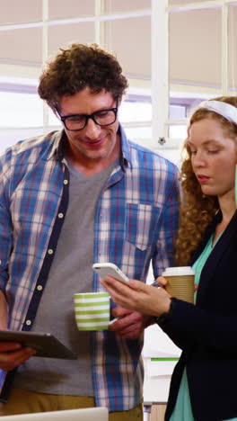 Group-of-business-executives-having-coffee-while-interacting-over-digital-tablet