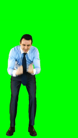 Excited-businessman-standing-against-green-background