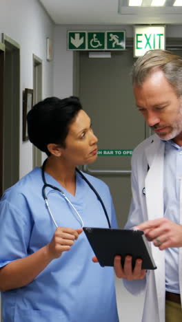 Male-doctor-and-colleague-discussing-over-digital-tablet