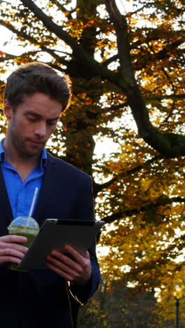 Businessman-having-coffee-while-using-digital-tablet