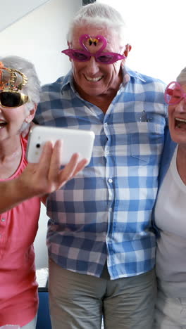 Senior-citizens-taking-selfie-on-mobile-phone-during-birthday-party