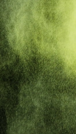 Green-and-yellow-dust-powder-blowing-against-black-background