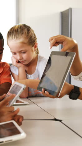 Teacher-teaching-kid-on-digital-tablet-in-library