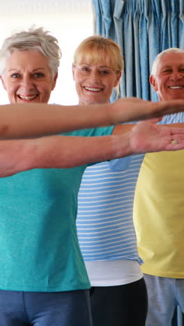 Trainer-assisting-senior-citizens-in-practicing-yoga