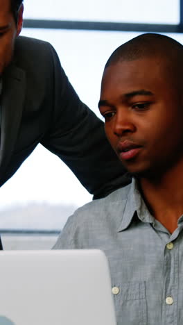 Business-executives-discussing-over-laptop