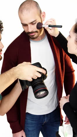 Model-getting-face-make-up-while-interacting-with-photographer