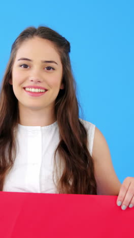 Beautiful-woman-holding-blank-placard-on-blue-background