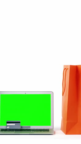 Multicolored-shopping-bags-and-laptop-on-white-background