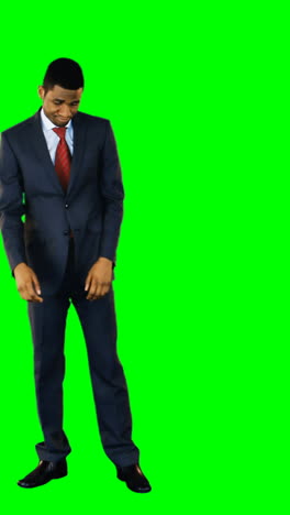 Tensed-businessman-standing-against-green-background