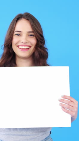 Beautiful-woman-holding-blank-placard-on-blue-background