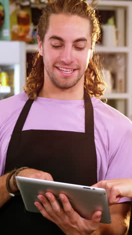 Smiling-waiter-and-waitress-using-digital-tablet-at-counter