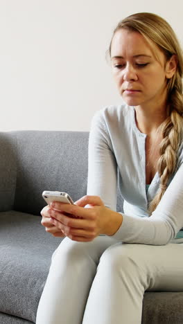 Frau-Benutzt-Mobiltelefon-Auf-Sofa-Im-Wohnzimmer