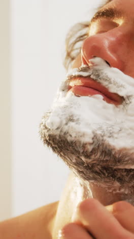 Man-using-a-razor-to-shave-his-beard-off