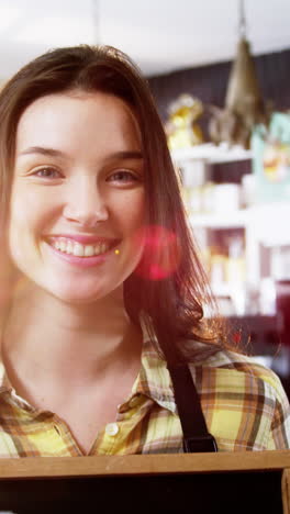 Smiling-waitress-showing-chalkboard-with-open-sign