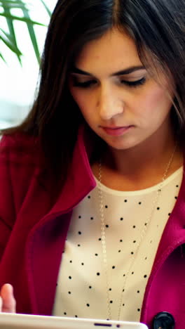 Businesswoman-using-digital-tablet-while-having-cup-of-coffee