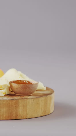 Different-types-of-cheese,-tomatoes-and-bowl-of-jam-on-wooden-board