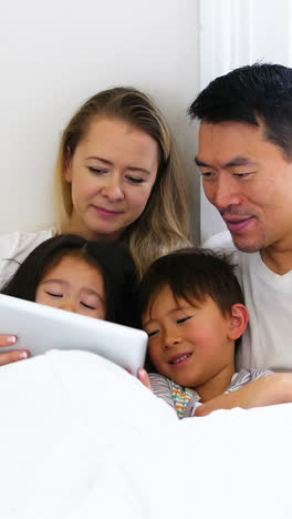 Glückliche-Familie,-Die-Sich-Im-Bett-Entspannt-Und-Ein-Digitales-Tablet-Nutzt