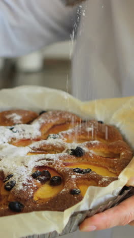 Nahaufnahme-Einer-älteren-Frau,-Die-Frisch-Gebackene-Torte-Mit-Puderzucker-Bestreut