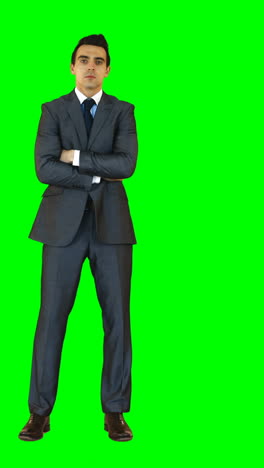 Businessman-standing-with-arms-crossed-against-green-background