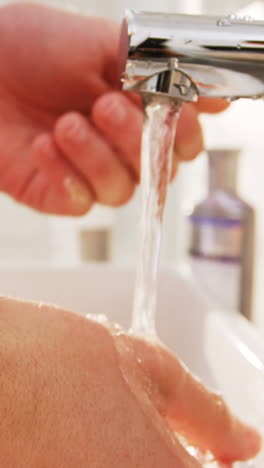 Man-washing-his-hands-in-bathroom-sink