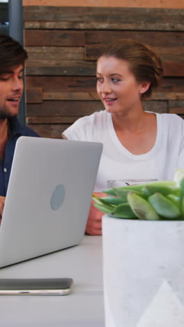 Business-executives-discussing-over-laptop