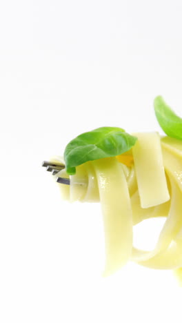 Close-up-of-cooked-pasta-with-basil-on-fork