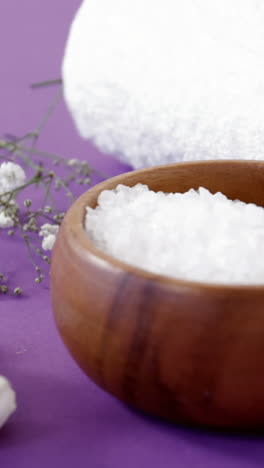 Sea-salt-in-wooden-bowl,-towel-and-flowers