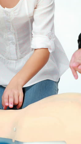 Two-male-paramedics-giving-a-demo-on-a-dummy-with-a-girl-child