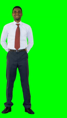 Businessman-standing-and-smiling-against-green-background