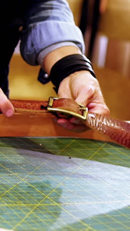 Mid-section-of-craftswoman-making-leather-belt