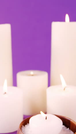 Sea-salt-in-wooden-bowl,-oil-and-candles-on-table