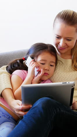 Mutter-Und-Tochter-Nutzen-Digitales-Tablet-Im-Wohnzimmer