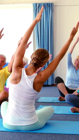 Trainer-assisting-senior-citizens-in-practicing-yoga