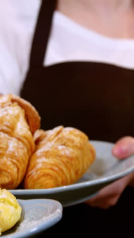 Waitress-holding-a-plate-of-croissant-and-sweet-food