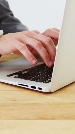 Mid-section-of-businessman-working-on-laptop