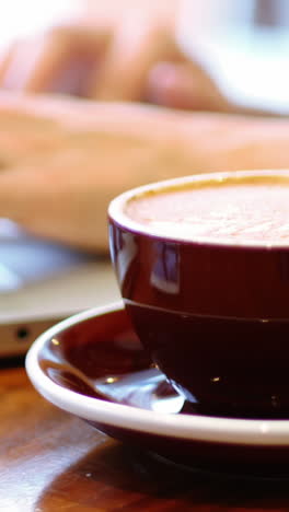 Businesswoman-using-laptop-with-coffee-cup-on-table