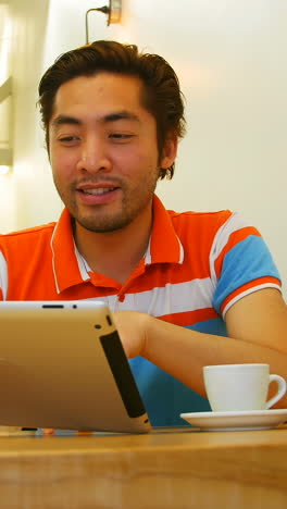 Man-using-digital-tablet-while-having-coffee-cup-on-table