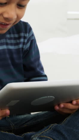 Boy-using-digital-tablet-while-relaxing-on-bed