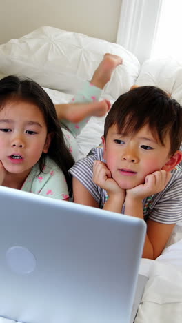 Niños-Usando-Laptop-En-La-Cama