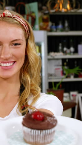 Portrait-of-waitress-holding-a-plate-with-a-cupcake