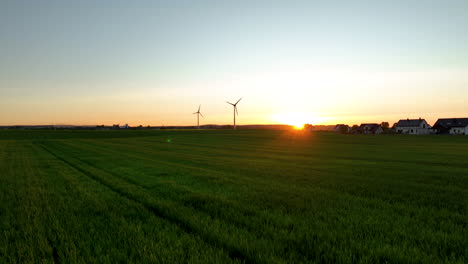 Ländliche-Szene-Mit-Bauernhaus-Und-Windturbinen-In-Rapsfeldern-Bei-Sonnenuntergang