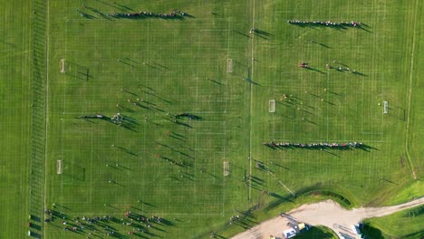 Vista-Aérea-De-Arriba-Hacia-Abajo-De-Personas-Jugando-En-Tres-Campos-De-Fútbol-En-Un-Día-De-Verano-Al-Atardecer