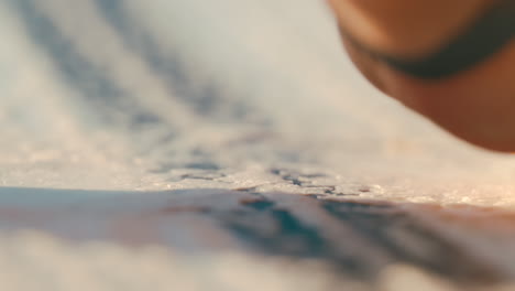 Slow-motion-close-up-of-female-hand-waxing-a-wake-surfboard-deck-to-get-good-grip-with-white-wax-in-preparation-to-surf