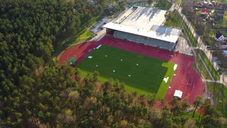 Track-and-field-stadium-in-aerial-approaching-view-with-golden-hour-sunlight