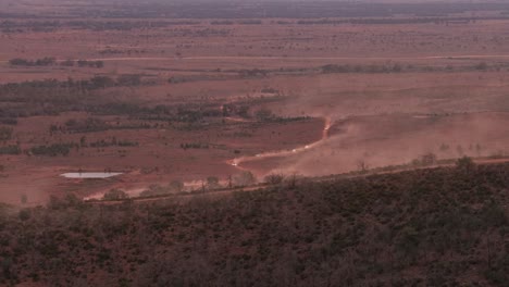 Four-wheel-drive-vehicles-kicking-up-dust-as-they-drive-along-a-track-towards-the-camera-in-the-outback-of-Australia