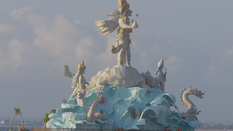 La-Magnífica-Estatua-De-Triratna-Amreta-Bhuwana-En-Kuta,-Bali,-Indonesia,-Se-Alza-Contra-El-Cielo-Azul.