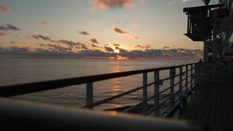 Sunset-Serenade:-Captivating-View-of-the-Sun-Setting-Behind-the-Ship's-Railing,-Aboard-a-Cruise-Ship-on-the-Open-Sea