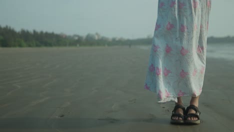 A-indian-lady-woman-legs-is-standing-on-a-beach-wearing-a-floral-dress-in-India